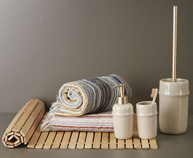 Baderomsmatte i bambus, beige baderomssett og stripete badehåndklær