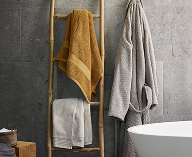 Karrygult og beige håndkle og en badekåpe