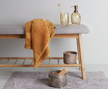 Karrigult håndkle i 100% bomull på en benk på et bad