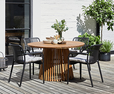 Elegant bord i hardtre med spiler og 4 stk sorte stablestoler til hagen