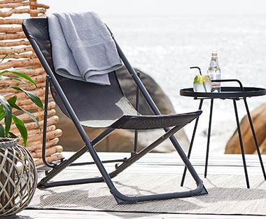Sammenleggbar campingstol i sort på en terrasse ved et bord