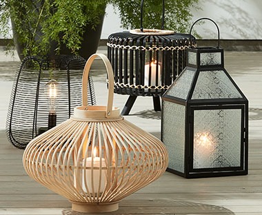 Fire stilige lanterner og batterilamper på en terrasse