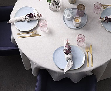 Et dekket bord med linduk og servise i lyse toner og farger