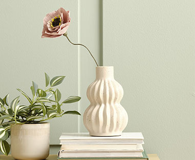 Skulpturell vase med riller og en papirblomst