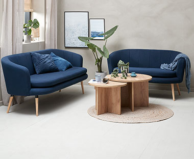 To blå sofaer og to runde stuebord i eik