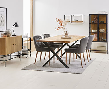 Elegant spisebord med sorte ben og naturfarget bordplate med grå spisestoler i fløyelstrekk