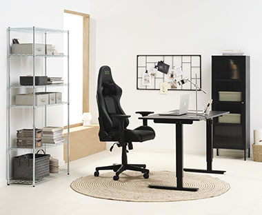 Sort gamingstol, hev og senk bord og sort skap på et kontor