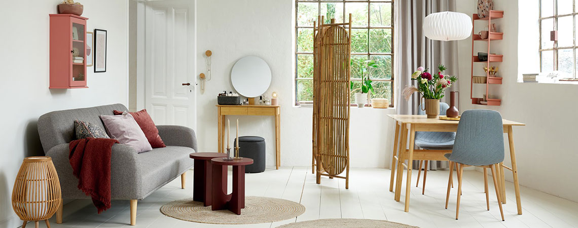 Stue/spisestue med rosa veggskap, grå sovesofa, skillevegg  i bambus, skrivebord i bambus og grå spisestoler