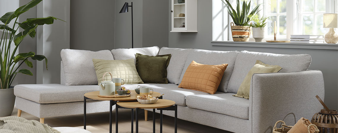 Stue med grå sofa og oransje, grønne og beige puter