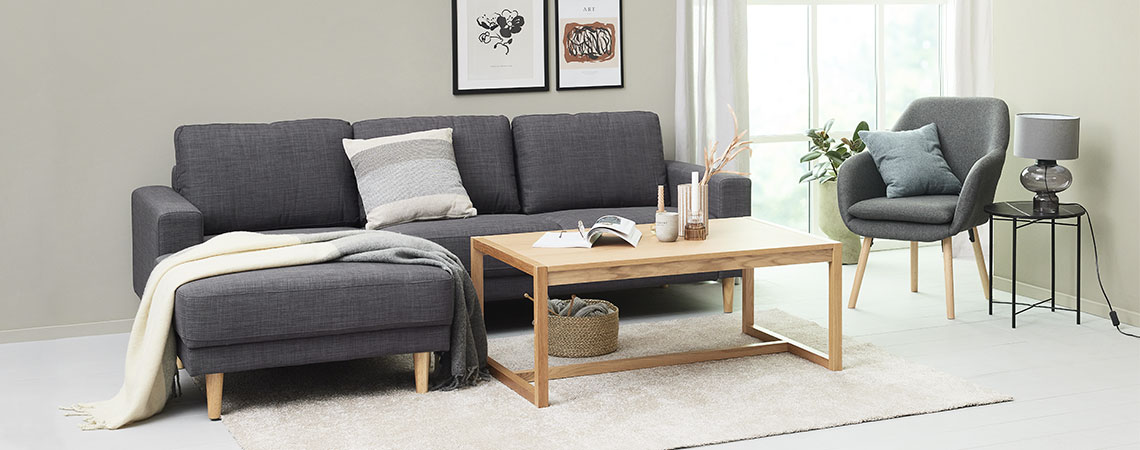 Stue med en sofa, sofabord og lenestol og langhåret teppe på gulvet