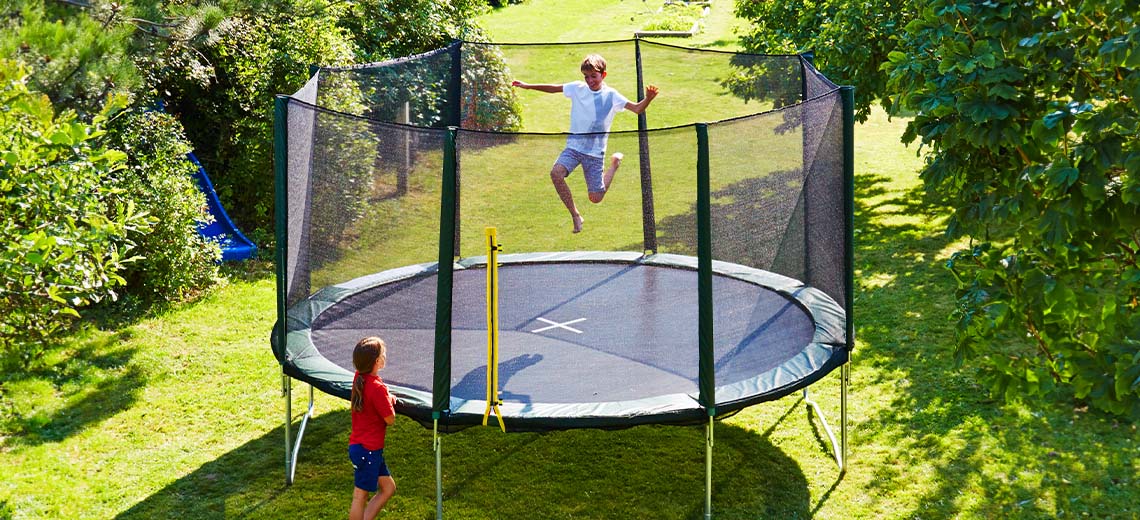 Barn som leker på en stor trampoline i hagen 