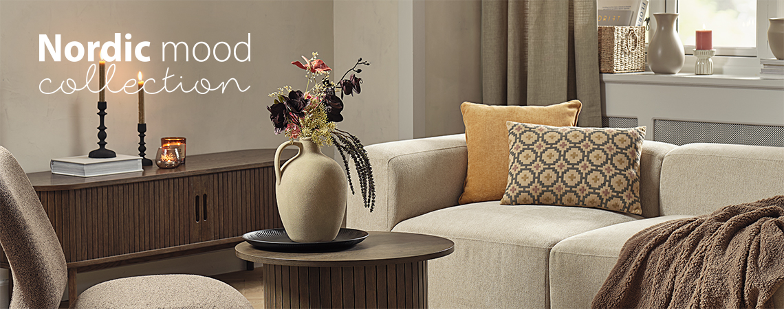 Sofa med mønstret pute og beige vase med kunstig bukett i en stue