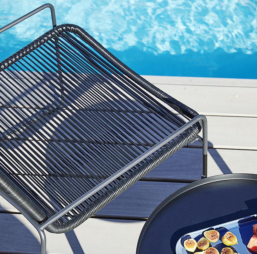 Bassengstol og sidebord på en solrik uteplass