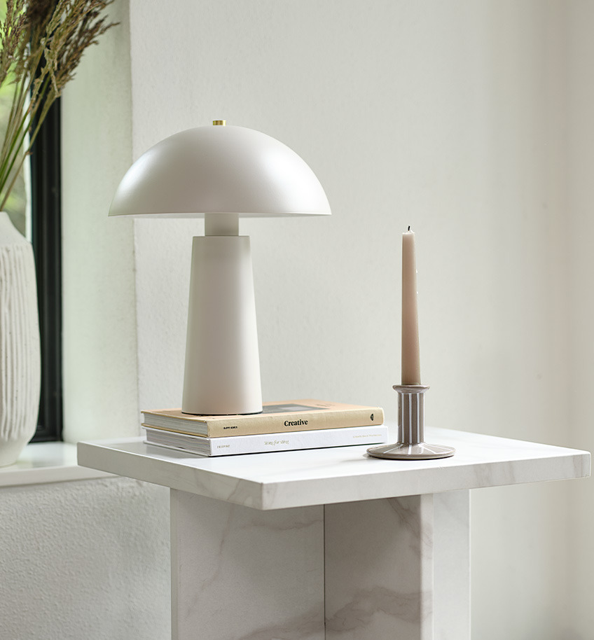 Klassisk bordlampe i lys beige/hvit med messingdetaljer på et marmorbord