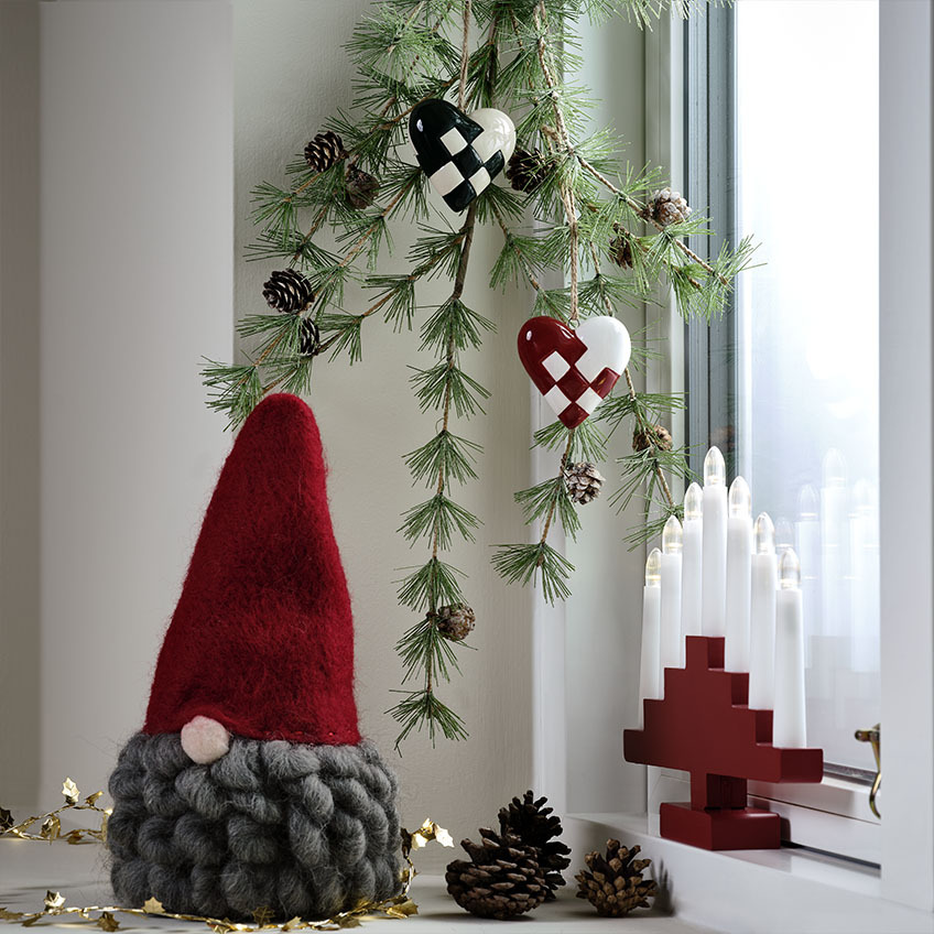 Skandinavisk julenisse med grått skjegg i en vinduskarm 