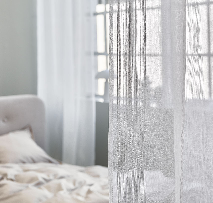 Hvite gardiner brukes til å skille et soveområde fra en stue