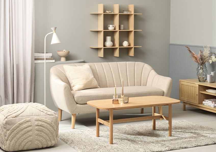 Beige 2,5-seters sofa, lys puff med spennende tekstur og et sofabord i eik