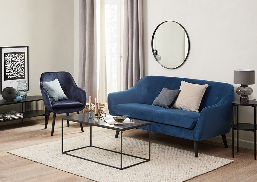 En stue med blå sofa og lenestol i fløyel