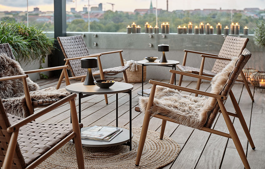 Lite hagebord med bordplate av fibersement og loungestoler på terrassen