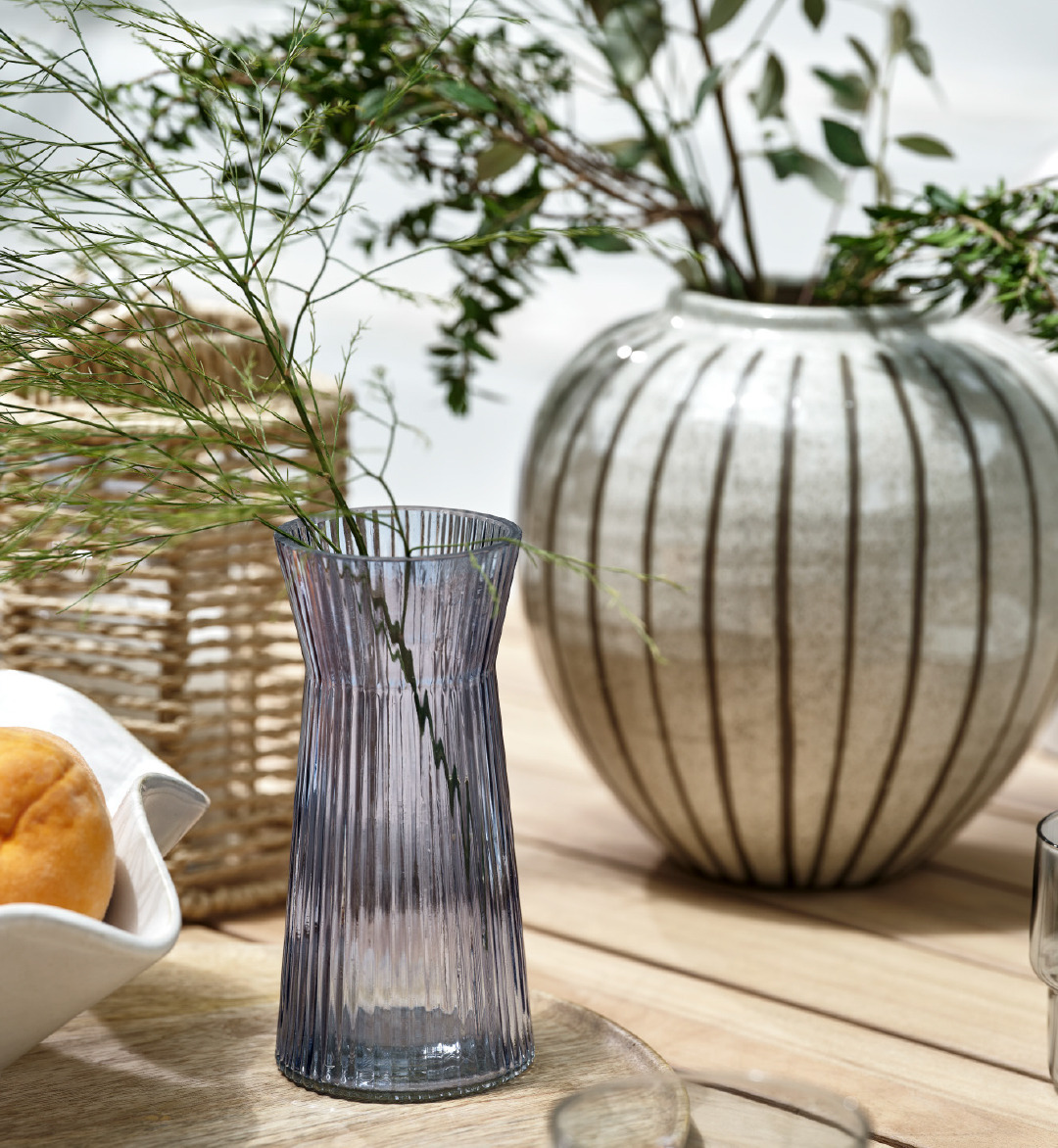 En glassvase og en stripete vase på et hagebord