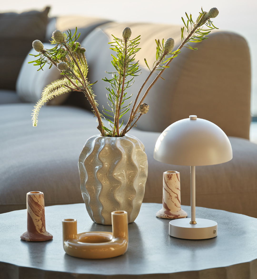 Et loungebord pyntet med vase, telysholdere og batterilampe
