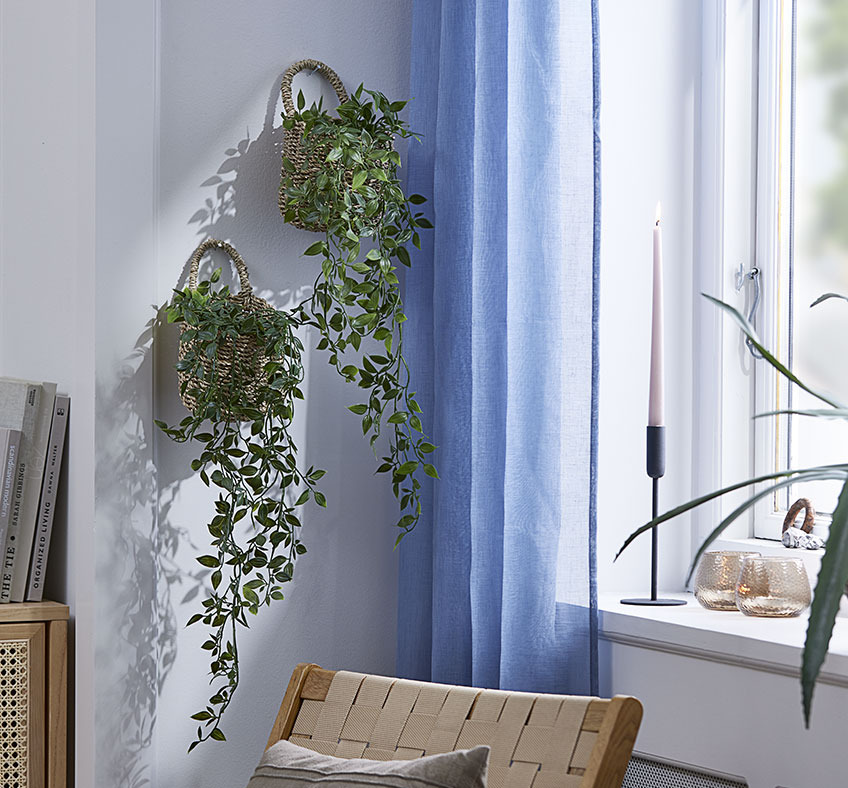 INGVER kurv med OLIVER kunstig plante To kurver med kunstige planter hengende på en stuevegg