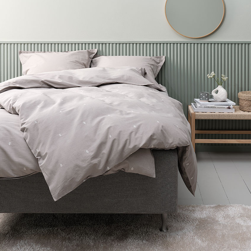Lyst grått dynetrekk og putetrekk i bomull på en seng i et soverom