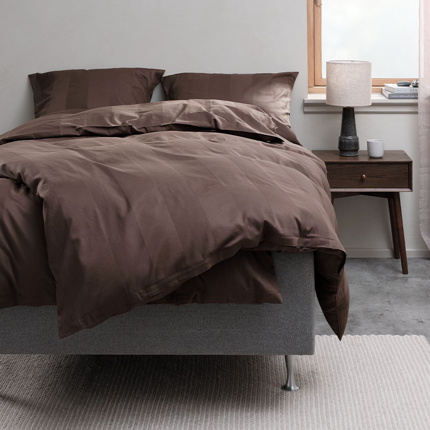 Sjokoladebrunt sengetøy i bomull og bambusviskose på en seng i et soverom