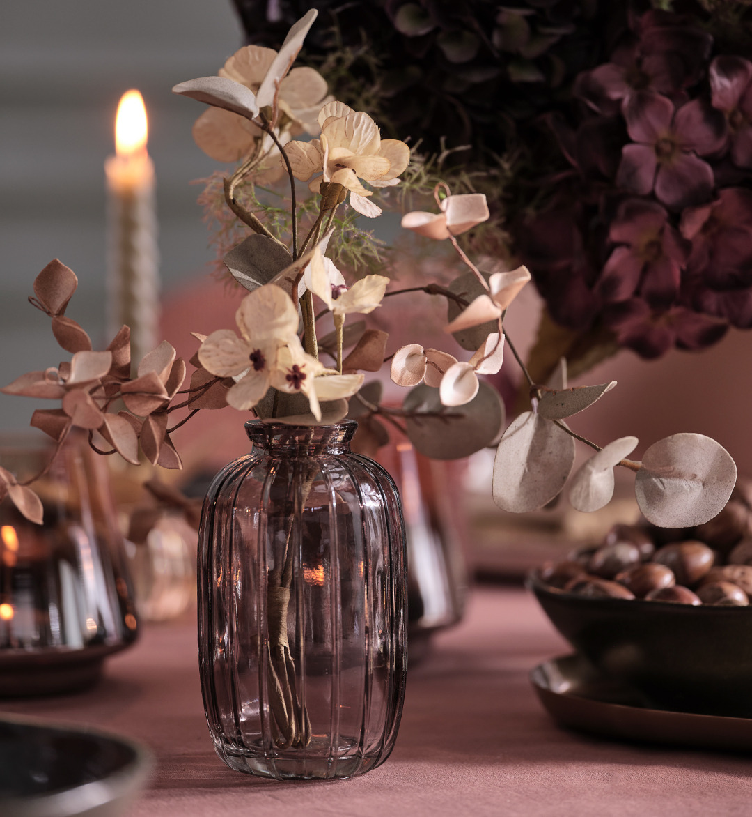 Grå glassvase med kunstige blomster på et bord