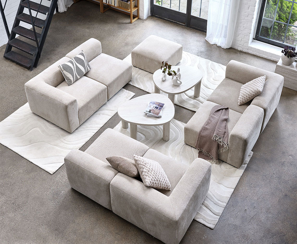 Beige modulsofa sentrert i et stort oppholdsrom