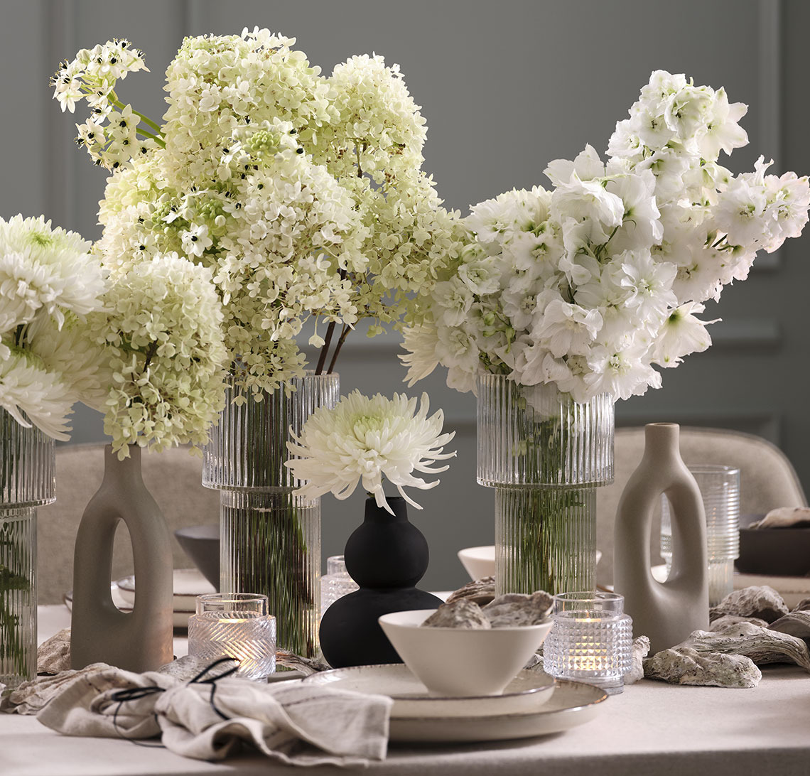 Svart vase og glassvaser med blomster på nyttårsbord