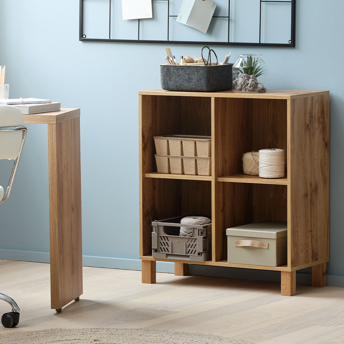 Modulær hylleenhet med fire rom, stående på gulvet med matchende ben.