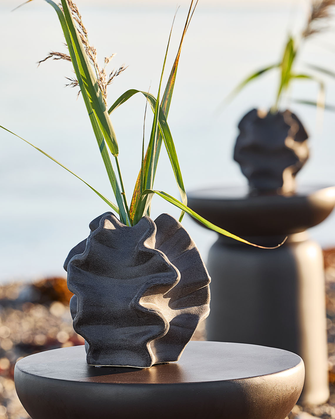 Vase med organisk form på en pidestall på en strand