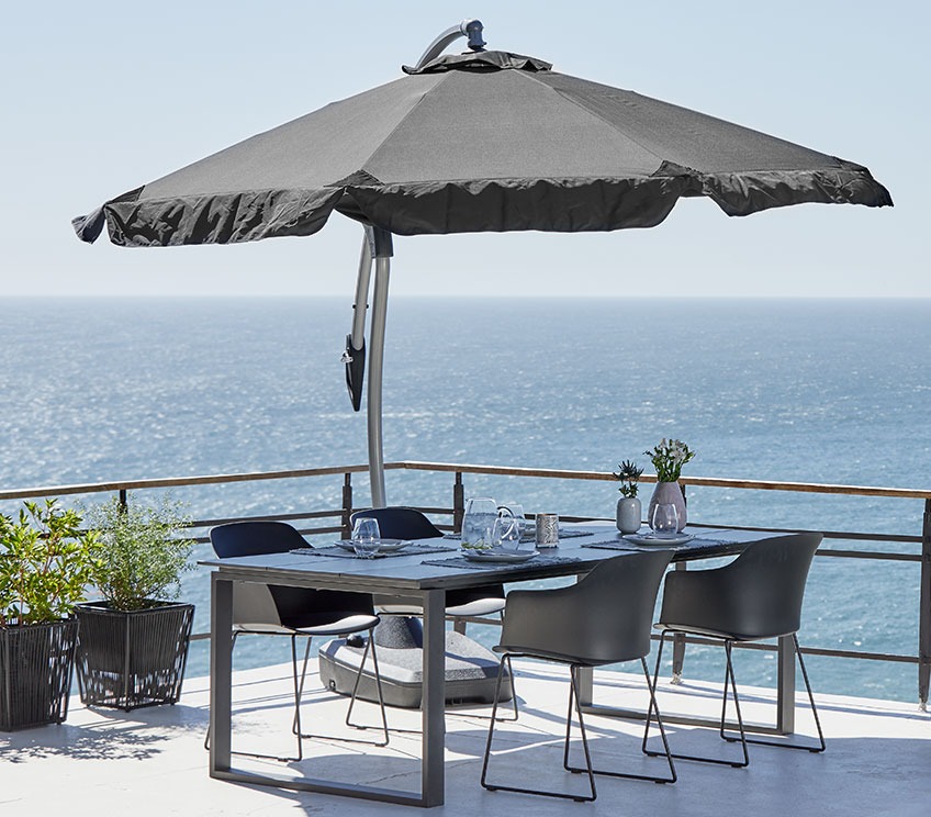 Patio with a hanging parasol over a garden set