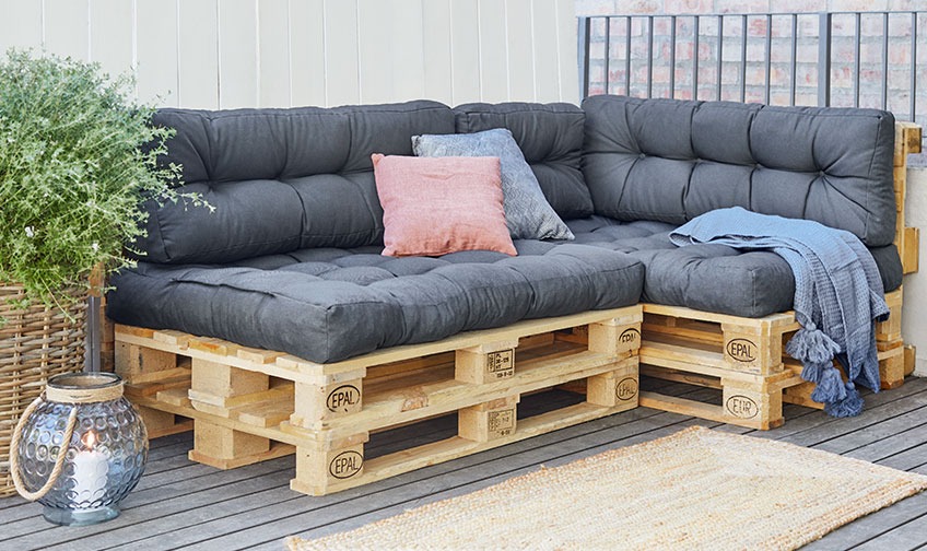 Pallesofa med puter og sleng på en uteplass