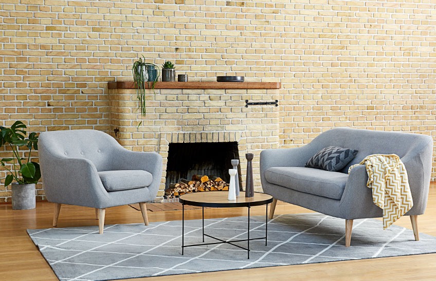En stue med en grå sofa, en grå lenestol og et salongbord