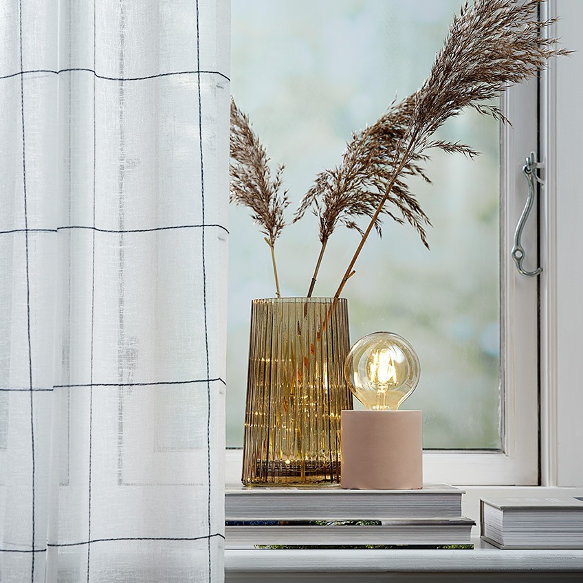 VIGRA curtains, ROY vase and ARNOLD battery lamp Lightweight curtains in a window with a vase and a battery lamp in the windowsill