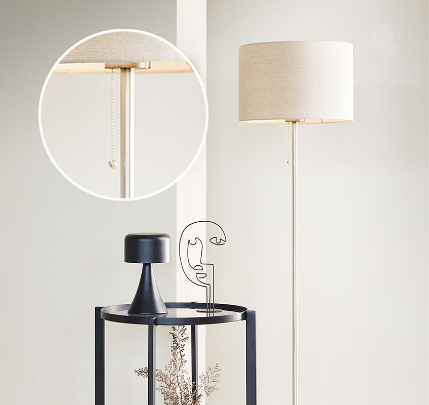 Hvit gulvlampe og svart sidebord med dekorative ornamenter