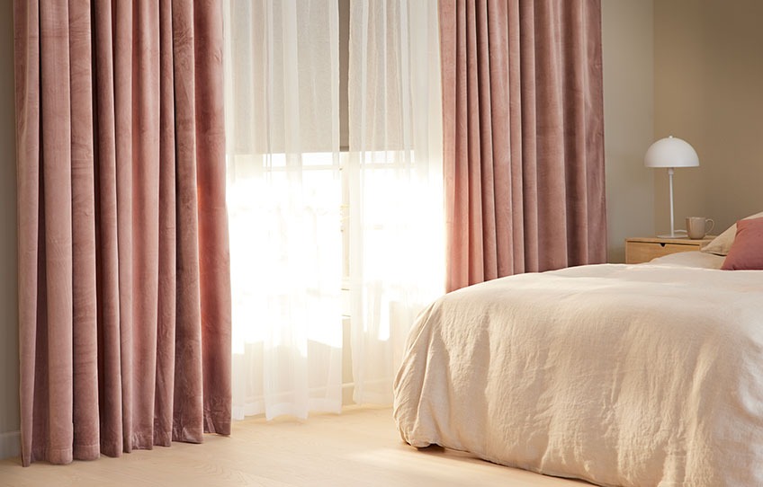 : Soverom med lysblokkerende rullegardiner halvveis opp og florlette gardiner så vidt åpne