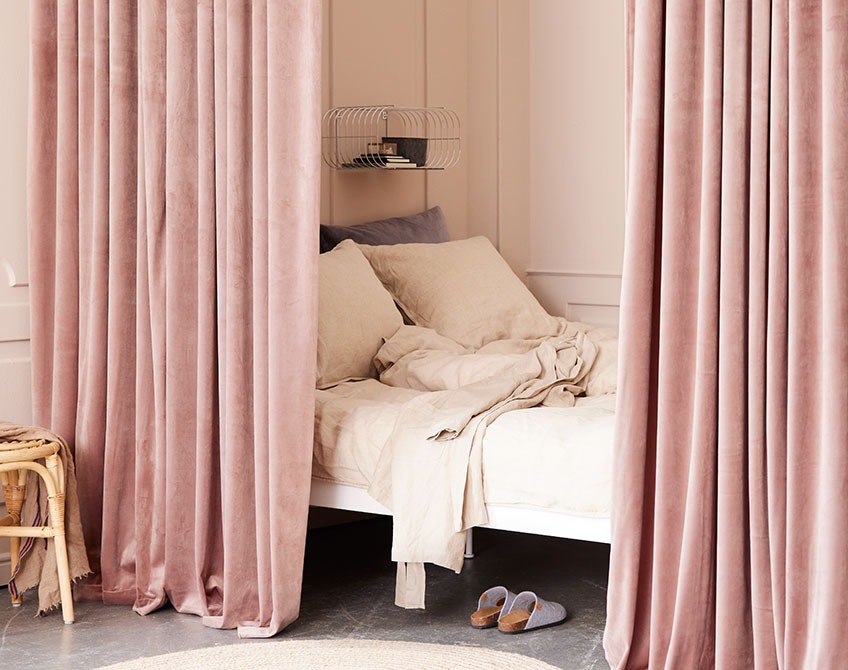Rosa gardiner som brukes til å skille ut et soveområde i en stor stue