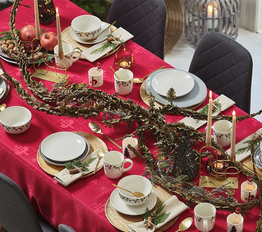 Bord dekket til juleselskap med rød duk og gullbestikk 