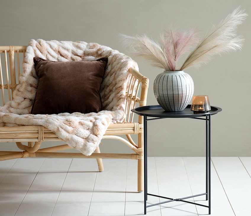 LISELEJE sofa med ERANTHIS pledd i syntetisk pels og BERBERIS pute. RANDERUP sidebord med SOFUS vase og BRYNJE telysholder Sofa med pledd i syntetisk pels og brun pute. Svart sidebord med vase og telysholder