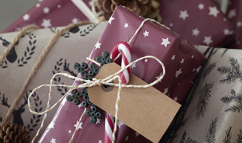 Julegave pakket inn i papir og pyntet med polkastang og perler