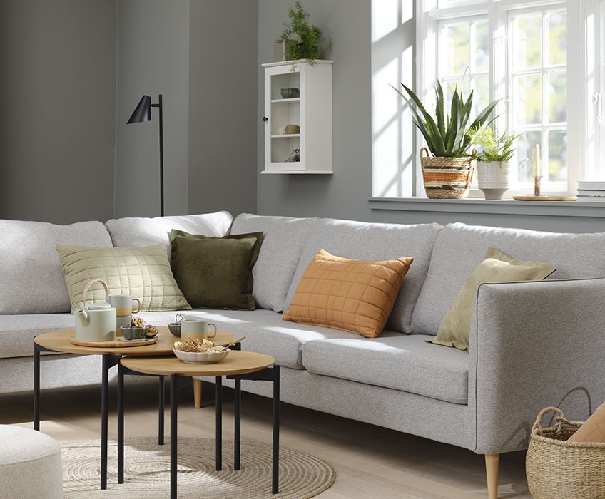 Stue med grå sofa og oransje, grønne og beige puter