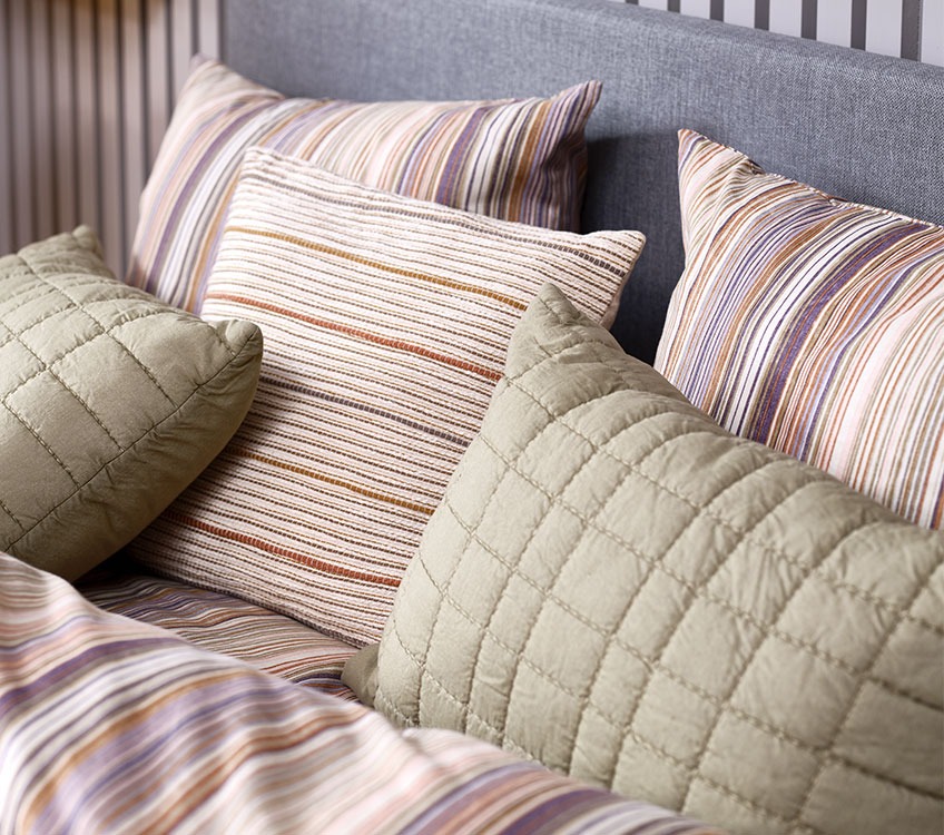 Stripete sengetøy med stripete dekorative puter og grønne puter