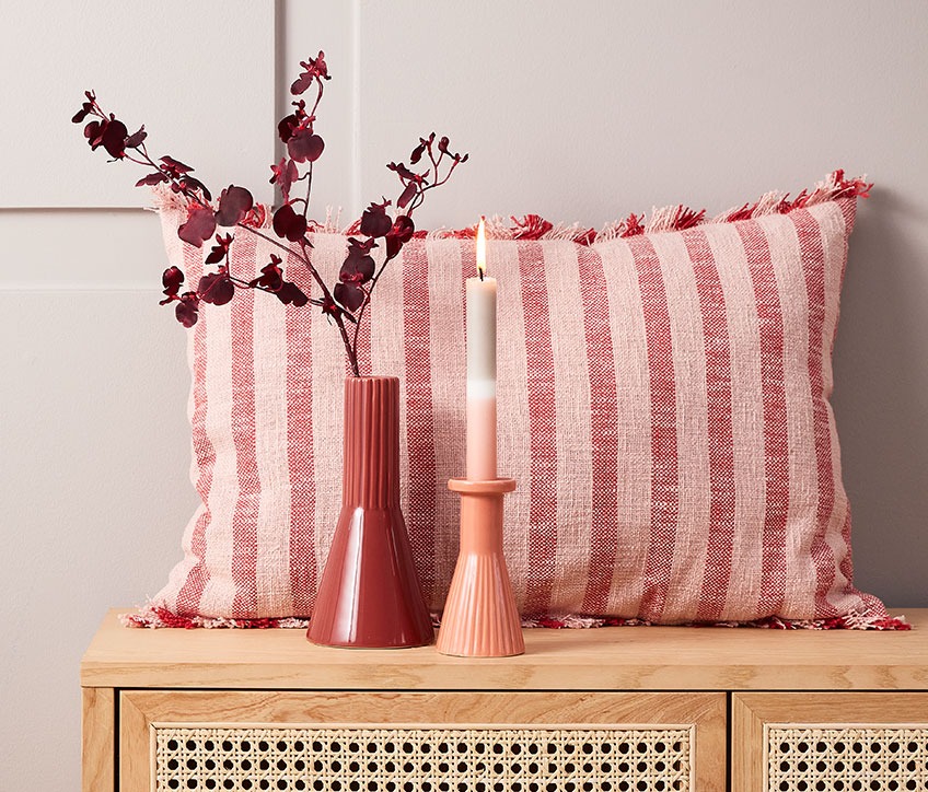 DAGFIOL pute, RAGNAR kunstige blomster, EGMUND vase og THRISTAN lysestake med IGNI stearinlys Stripet pute bak rød vase og lysestake med stripet stearinlys