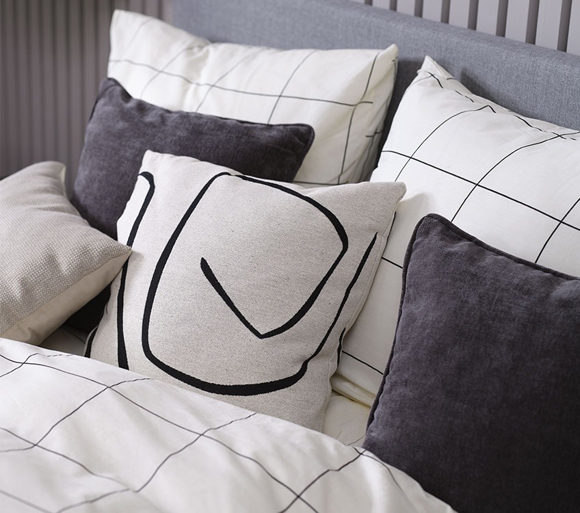 Soverom med sengesett i hvitt og svart og med dekorative puter i harmonerende fargetoner