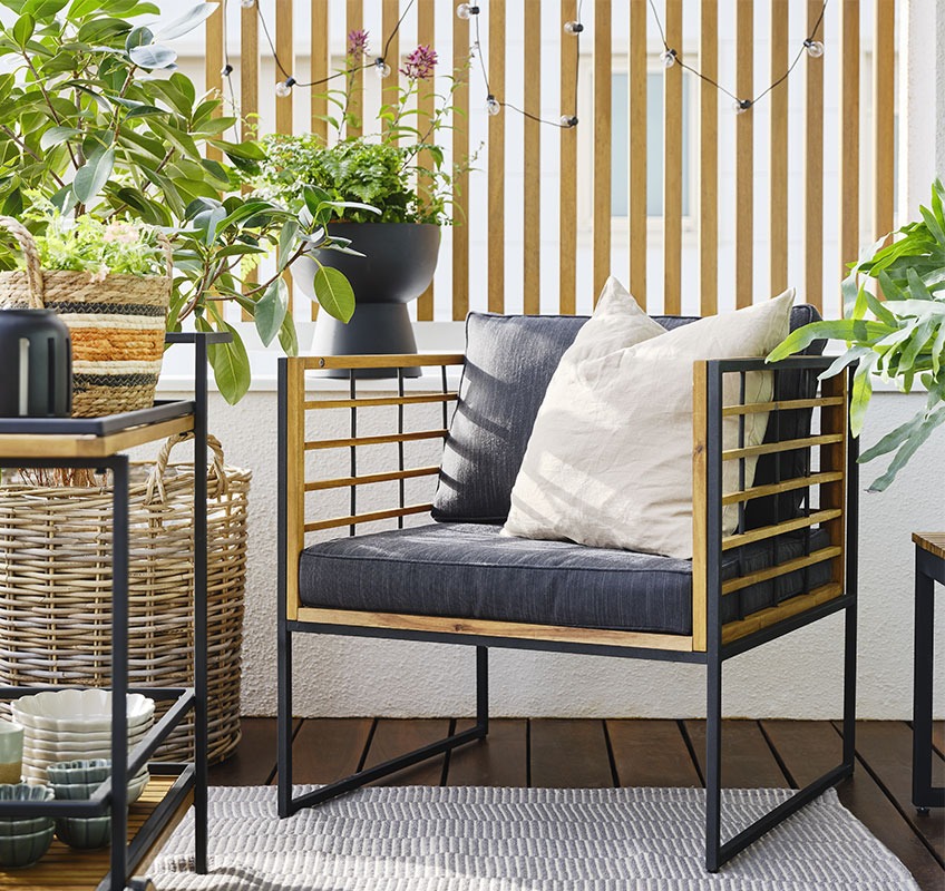 Balkong med loungestol i sort og tre, med grønne planter