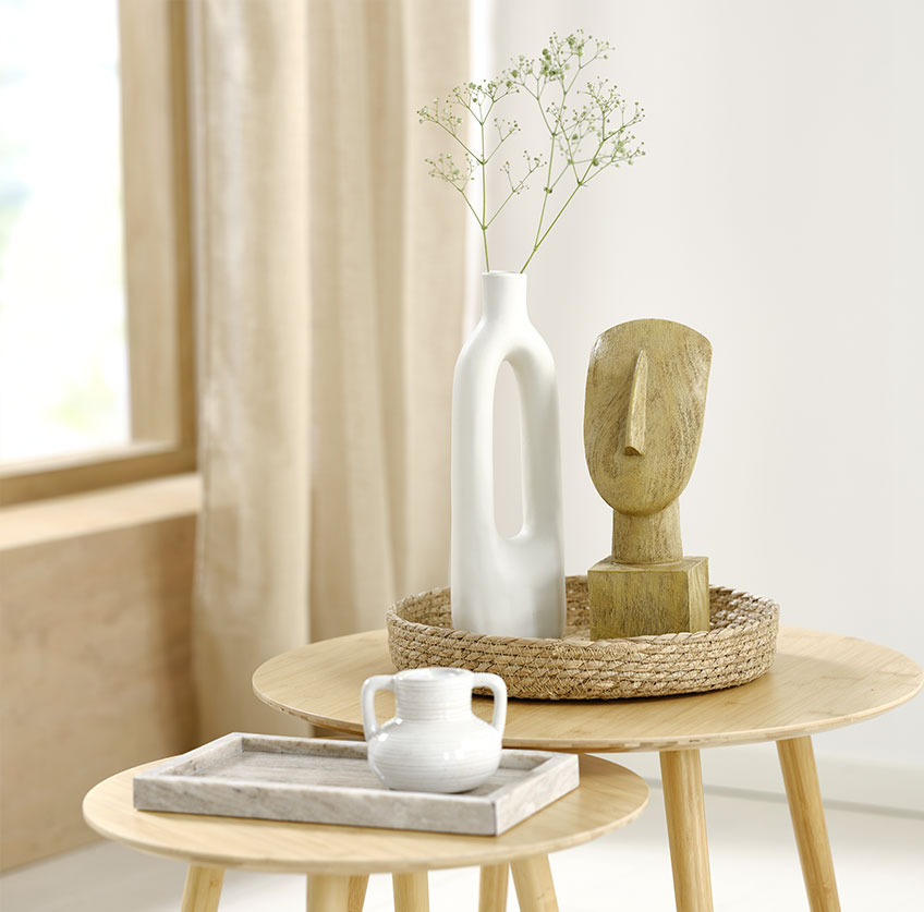 Marmorbrett med hvit telysholder og et sjøgressbrett med en hvit vase og en skulptur