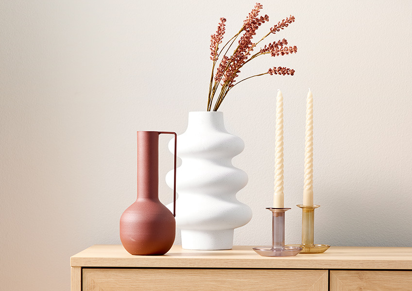 Dekorasjoner på toppen av en skjenk med vase og kunstige blomster